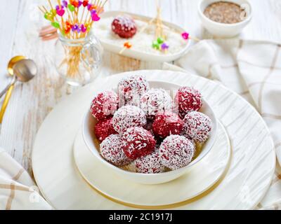 No-Bake Beere Bliss Kugeln mit ausgekockten Kokosnuss und Chia Samen gemischt mit Erdnussbutter und Himbeeren, Brombeeren, Heidelbeeren auf einer weißen Schüssel Stockfoto