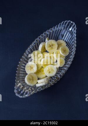 Bananenscheiben in Glasschale auf schwarzem Hintergrund - Draufsicht Foto Stockfoto