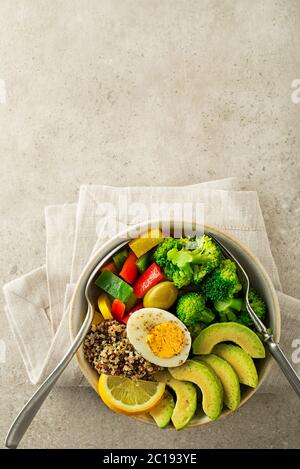 Gesundes Salatessen mit Quinoa, Ei, Avocado und gemischtem frischem Gemüse auf grauem Grund Draufsicht. Lebensmittel und Gesundheit. Gesundes Essenskonzept Stockfoto