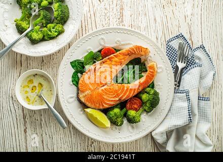 Frisch gebackenes Lachssteak mit Dressing und Gemüse auf dem Teller Stockfoto
