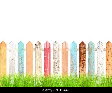 Rustikaler Holzzaun und grünes Gras. Alte Zaun mit Vintage-Bretter mit rissiger Farbe rot, weiß, braun, orange und blau. Isoliert auf weiß b Stockfoto