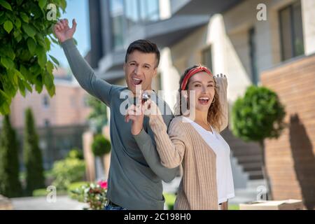 Glückliches junges Paar, das sich nach dem Schlüssel aus ihrem neuen Haus großartig fühlt Stockfoto