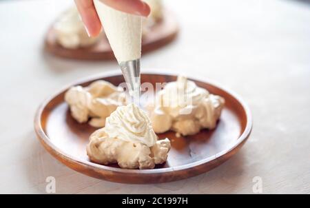 , die Meringue mit Sahne aus der kulinarischen Tasche schmücken Stockfoto