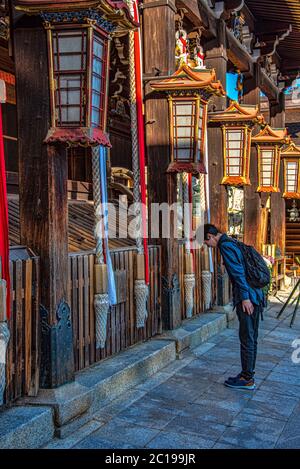 Junger Mann, der im Kitano Tenmangu shinto-Schrein, Kyoto, Japan betet Stockfoto