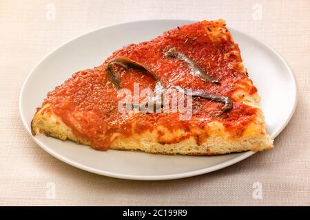 Eine Scheibe Marinara Pizza mit Sardellenbestich auf Tomatenmark in der Nähe serviert auf einem generischen weißen Teller Stockfoto