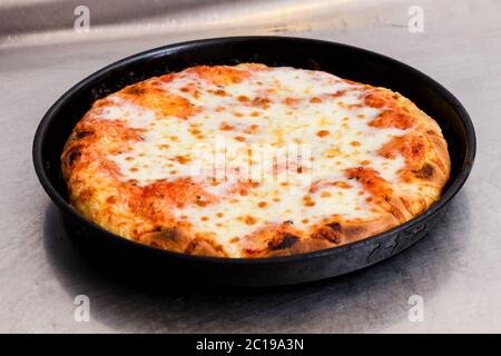 Frisch gebackene oder gegrillte italienische Margherita Pizza in einem runden Backblech auf einer Küchentheke in einer Pizzeria Stockfoto