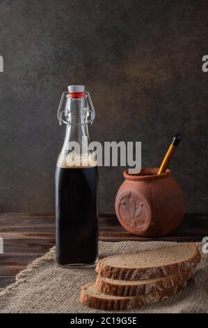 Hausgemachte tradisionale russische Kvass mit Glas Tasse und Brot. Hinter einem Tontopf mit einem Holzlöffel. Wunderbar gesundes Erfrischungsgetränk für den Sommer Stockfoto