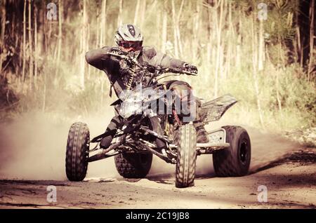 ATV Racer nimmt eine Wendung während eines Rennens auf einem staubigen Gelände. Stockfoto