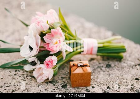 Brautstrauß aus Tulpen und Anemonen, eine Geschenkbox mit einem Ehering darauf Stockfoto