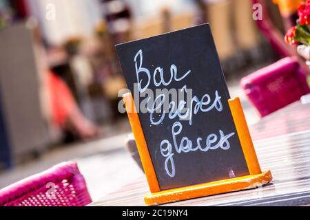 Kleine Speisekarte mit schwarzen Brettscheiben, auf der Bar, Eiscreme und Pfannkuchen (Bar Crepes Glaces auf Französisch) auf einem Tisch im Freien stehen Stockfoto