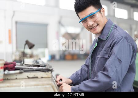 Junger asiatischer Mann arbeitet in der Werkstatt Stockfoto