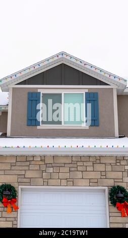 Vertikale Home Fassade mit festlichen Weihnachtskränzen und bunten Sehnen im Winter Stockfoto