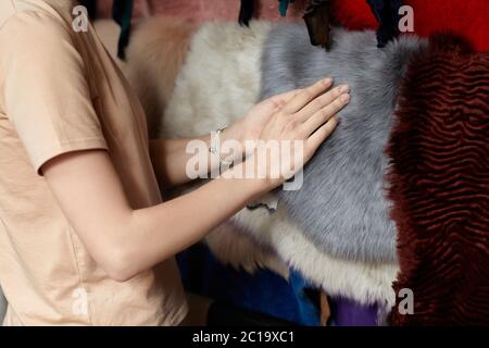 Frau im Lager von Pelz. Verschiedene Arten von bunten Pelzfellen. Stockfoto