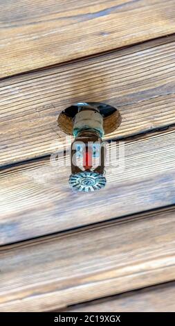 Vertikaler Rahmen Sprinkler, installiert an der braunen Holzdecke eines Gebäudes oder Hauses Stockfoto