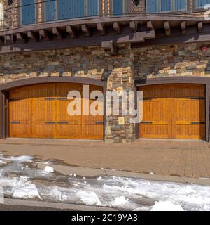 Quadratische Fassade des Hauses mit zwei aufklappbaren Holz Garagentüren und Steinmauer Stockfoto