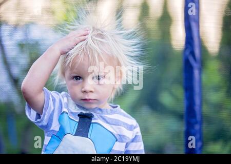 Süße kleine Jungen mit statischen electricy Haar, in seiner komischen Porträt im Freien auf einem Trampolin genommen Stockfoto