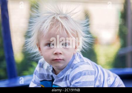 Süße kleine Jungen mit statischen electricy Haar, in seiner komischen Porträt im Freien auf einem Trampolin genommen Stockfoto