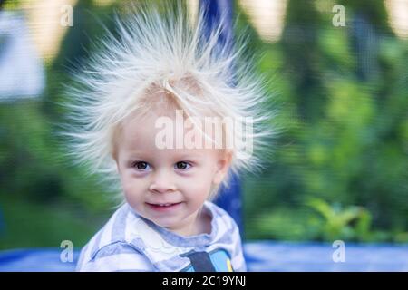 Süße kleine Jungen mit statischen electricy Haar, in seiner komischen Porträt im Freien auf einem Trampolin genommen Stockfoto