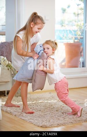 Zwei Kinder spielen Kissenschlacht zu Hause mit Kissen Stockfoto