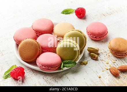 Teller mit verschiedenen Makronen auf rustikalem weißen Holztisch Stockfoto