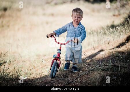 Glückliches Kleinkind mit kleinem Fahrrad in der Natur Stockfoto