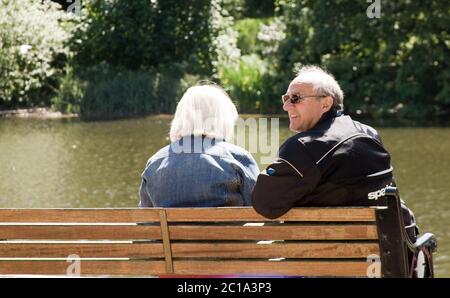 Altes Paar, das auf einer Bank mit Blick auf den Fluss sitzt Stockfoto