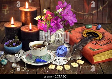 Romantisches Stillleben mit Tasse Tee, Hexenbuch, Runen und schwarzen Kerzen. Esoterische, Wicca und okkulten Hintergrund mit magischen Objekten, Glück sagen ein Stockfoto