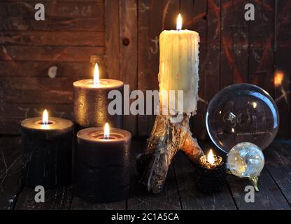 Brennende Kerzen und magische Kristalle auf Hexenholztisch. Esoterischer, wicca und okkulter Hintergrund mit magischen Objekten, Wahrsagerei und Weissagung Stockfoto