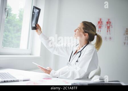 Ziemlich junge Ärztin schaut auf Röntgenaufnahmen Stockfoto