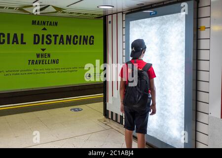 London, Großbritannien. Juni 2020. Coronavirus: Gesichtsschutz ist jetzt im öffentlichen Verkehr obligatorisch. Ein kleiner Junge reist auf einer Röhre.Soziale Distanzierung Plakatwand Stockfoto