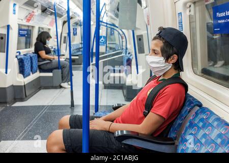 London, Großbritannien. Juni 2020. Coronavirus: Gesichtsschutz ist jetzt im öffentlichen Verkehr obligatorisch. Ein kleiner Junge mit Gesichtsmaske Reise auf einem Schlauch. Jeder trave Stockfoto