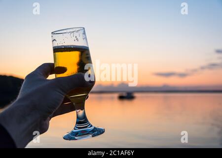 Ein frisches, kaltes Bier am Meer bei einem wunderschönen Sonnenuntergang Stockfoto