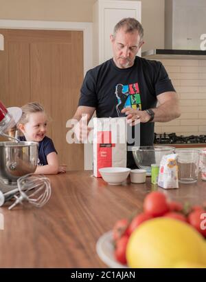 Papa und Tochter machen frischen Pizzateig in Küchenarmatur. Corona Lockdown Kochen. Pizza mit Papa beim Lockdown machen. Stockfoto