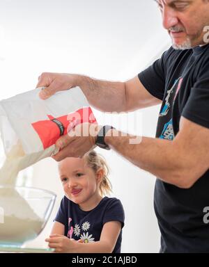 Papa und Tochter machen frischen Pizzateig in Küchenarmatur. Corona Lockdown Kochen. Pizza mit Papa beim Lockdown machen. Stockfoto