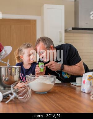 Papa und Tochter machen frischen Pizzateig in Küchenarmatur. Corona Lockdown Kochen. Pizza mit Papa beim Lockdown machen. Stockfoto