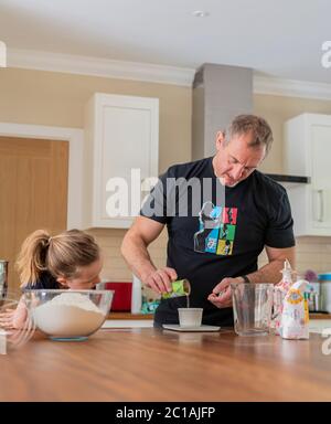 Papa und Tochter machen frischen Pizzateig in Küchenarmatur. Corona Lockdown Kochen. Pizza mit Papa beim Lockdown machen. Stockfoto