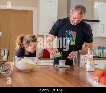 Papa und Tochter machen frischen Pizzateig in Küchenarmatur. Corona Lockdown Kochen. Pizza mit Papa beim Lockdown machen. Stockfoto