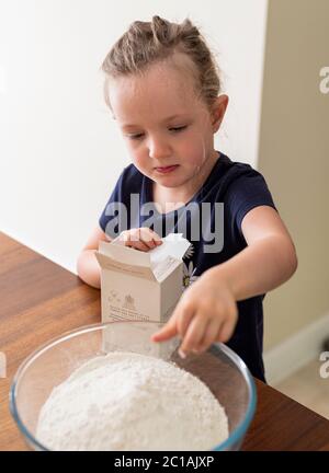 Papa und Tochter machen frischen Pizzateig in Küchenarmatur. Corona Lockdown Kochen. Pizza mit Papa beim Lockdown machen. Stockfoto