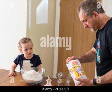 Papa und Tochter machen frischen Pizzateig in Küchenarmatur. Corona Lockdown Kochen. Pizza mit Papa beim Lockdown machen. Stockfoto