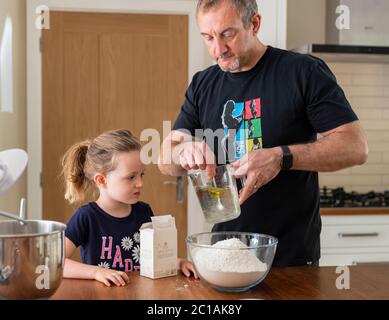 Papa und Tochter machen frischen Pizzateig in Küchenarmatur. Corona Lockdown Kochen. Pizza mit Papa beim Lockdown machen. Stockfoto