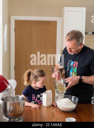 Papa und Tochter machen frischen Pizzateig in Küchenarmatur. Corona Lockdown Kochen. Pizza mit Papa beim Lockdown machen. Stockfoto