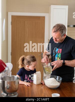 Papa und Tochter machen frischen Pizzateig in Küchenarmatur. Corona Lockdown Kochen. Pizza mit Papa beim Lockdown machen. Stockfoto