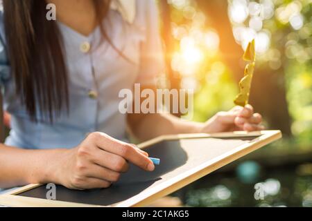 Die Hände verwenden die Kreide zum Zeichnen, das Balckboard in den Parks schreibendes. Bildung, Lernkonzept. Stockfoto