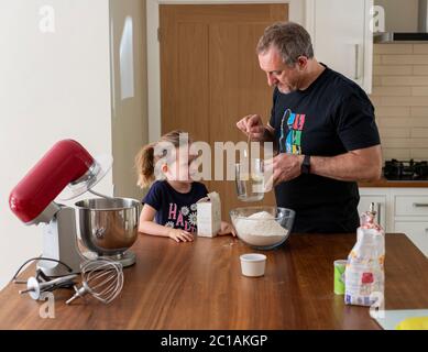 Papa und Tochter machen frischen Pizzateig in Küchenarmatur. Corona Lockdown Kochen. Pizza mit Papa beim Lockdown machen. Stockfoto