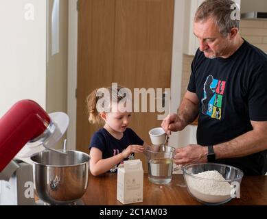 Papa und Tochter machen frischen Pizzateig in Küchenarmatur. Corona Lockdown Kochen. Pizza mit Papa beim Lockdown machen. Stockfoto