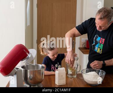 Papa und Tochter machen frischen Pizzateig in Küchenarmatur. Corona Lockdown Kochen. Pizza mit Papa beim Lockdown machen. Stockfoto