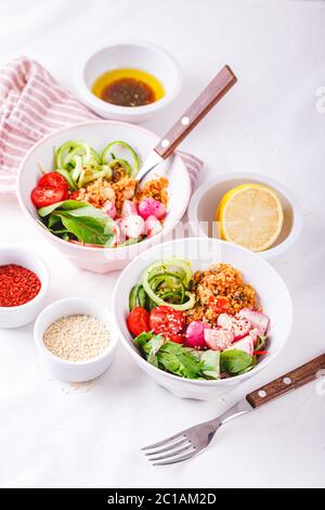 Salat mit Couscous, Huhn, Tomaten, Gurke, gerösteten Rettich und Mangold in einer Schüssel auf weißem Hintergrund. Gesunde Ernährung. Ketogene Ernährung. Stockfoto