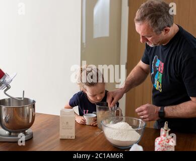 Papa und Tochter machen frischen Pizzateig in Küchenarmatur. Corona Lockdown Kochen. Pizza mit Papa beim Lockdown machen. Stockfoto