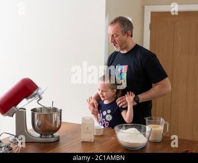 Papa und Tochter machen frischen Pizzateig in Küchenarmatur. Corona Lockdown Kochen. Pizza mit Papa beim Lockdown machen. Stockfoto