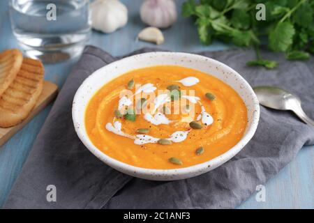 Puppkin-Cremesuppe, vegetarisches Mittagessen auf blauem Holztisch. Stockfoto